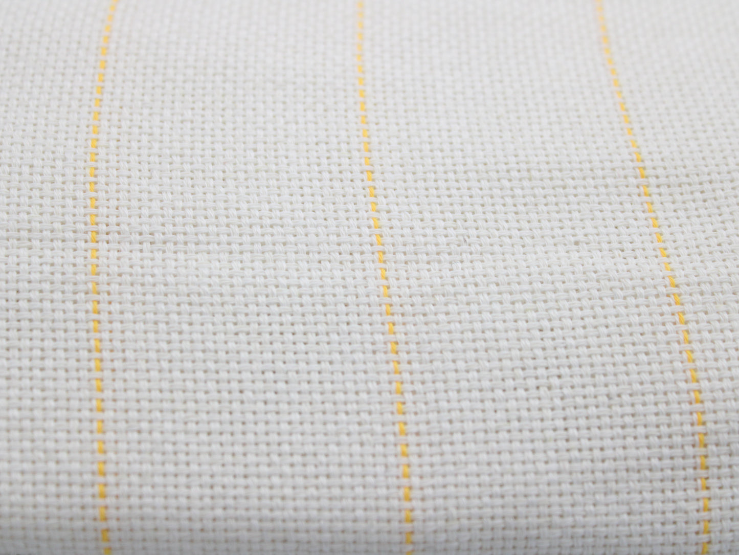Close-up of a white monks cloth with three thin vertical yellow guidlines