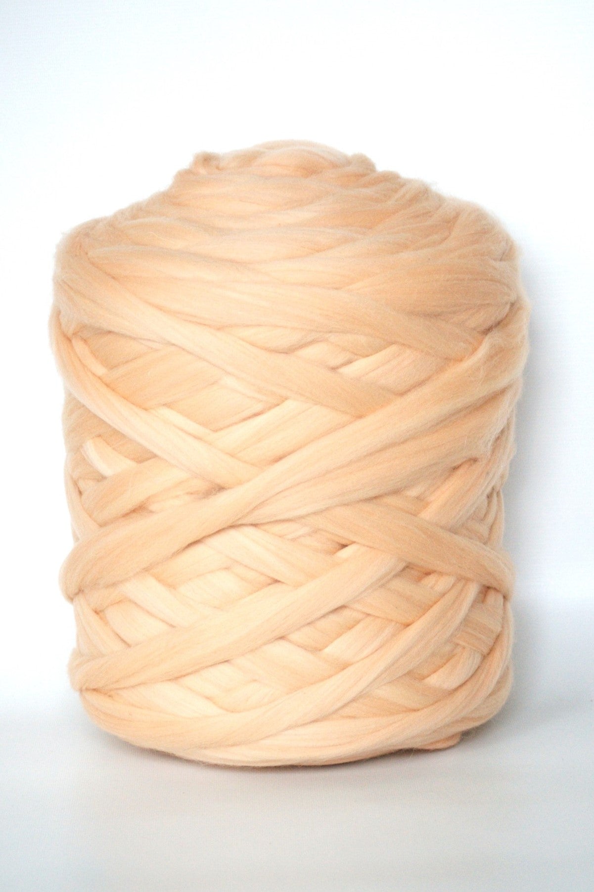 Large ball of peach-colored chunky yarn on a white background