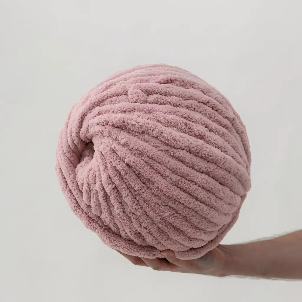 Large pink chenille ball of yarn held against a light gray background