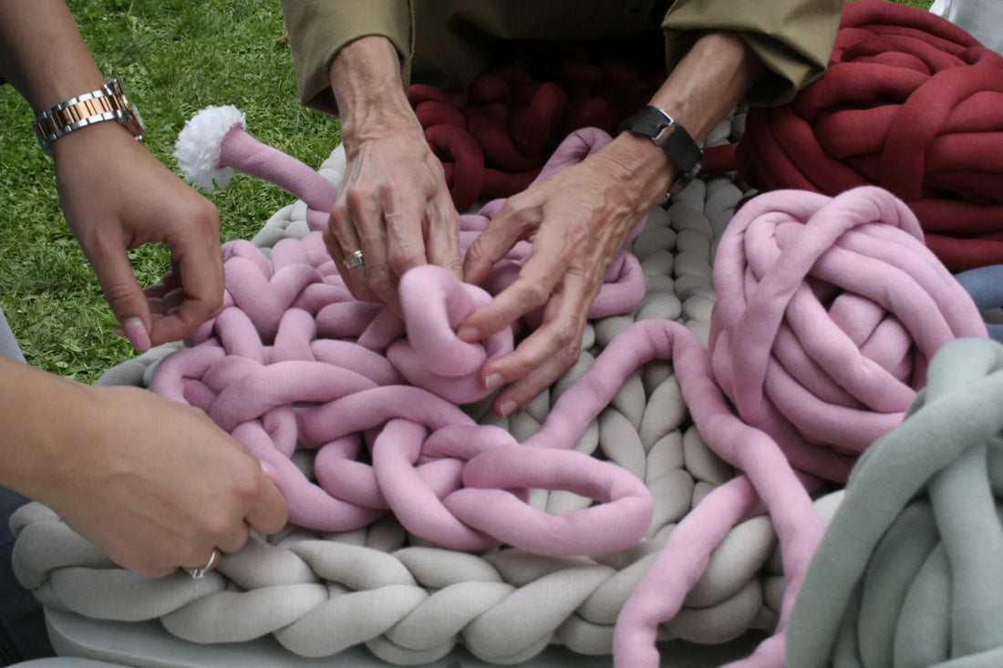 different women's hands trying to arm knit with tube yarn