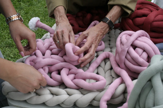 different women's hands trying to arm knit with tube yarn