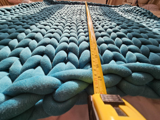 turqouise color chunky blanket on the floor measured  with ruler dimensions