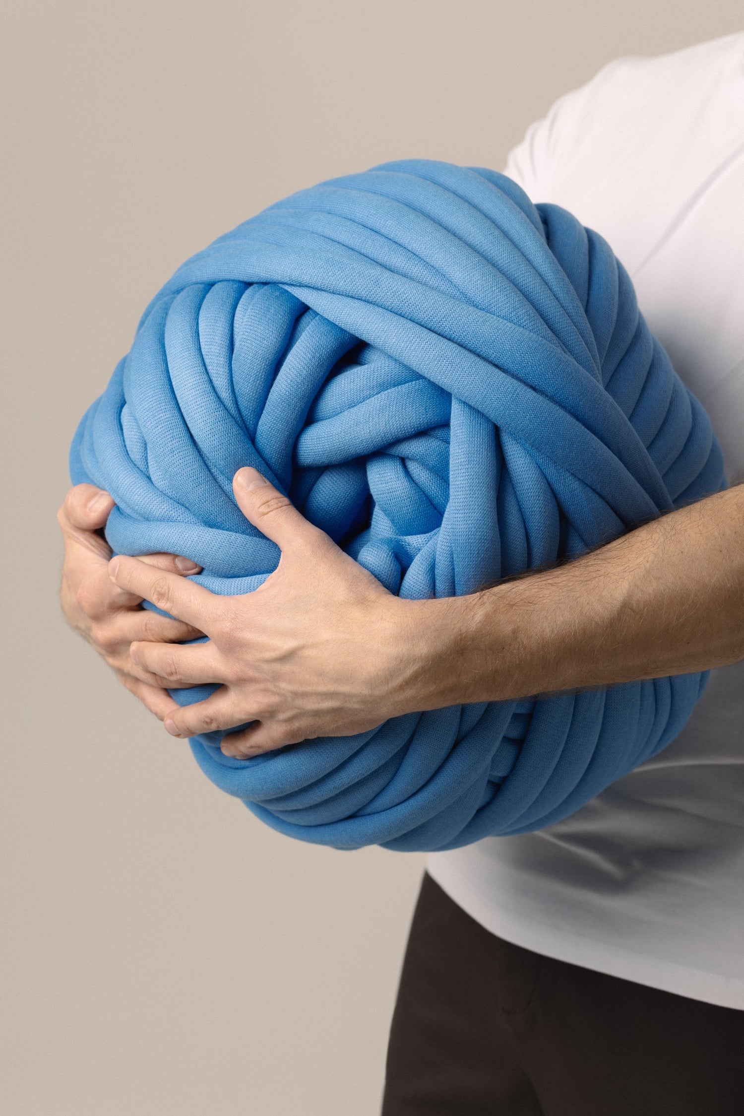 Man holding giant cotton yarn in beige background