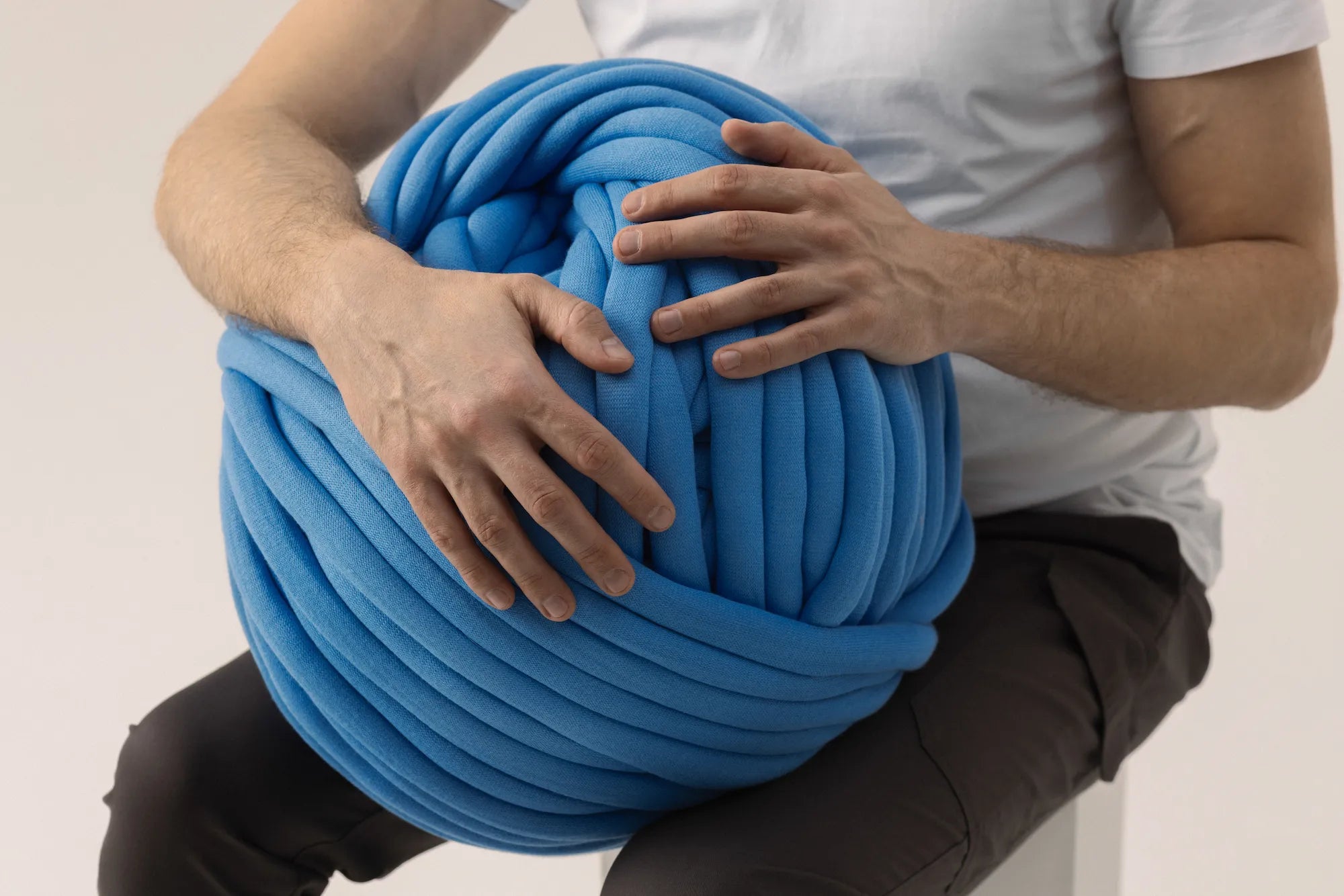 Person holding a large ball of blue yarn
