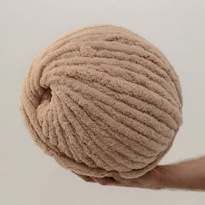 man holding beige color chenille yarn