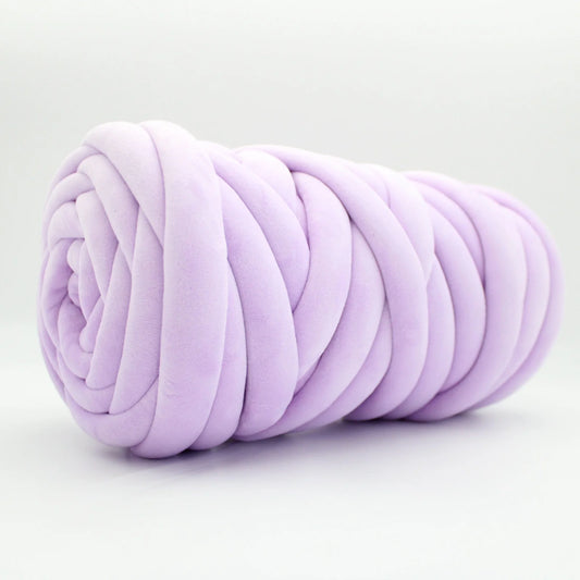 A lavender purple plush velvet tube yarn with a chunky, thick ribbed texture, rolled into a spiral shape and photographed on a clean white background.