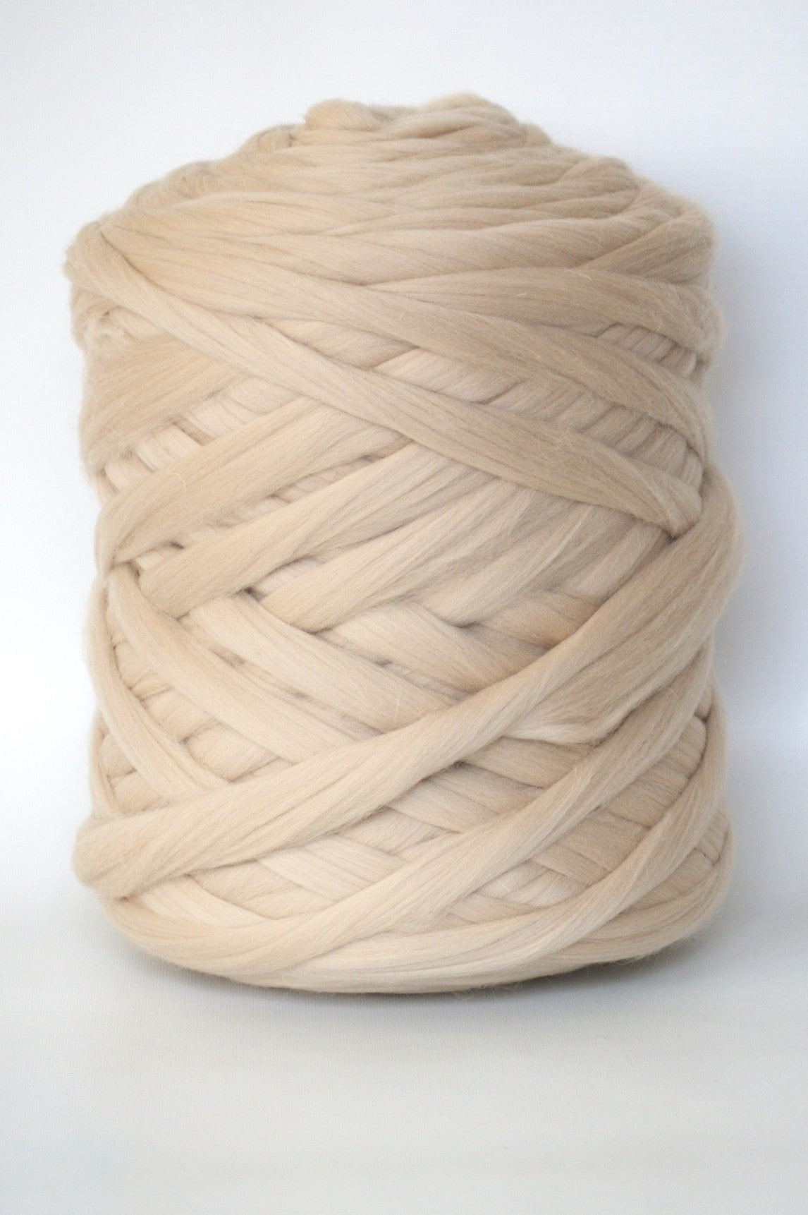 Large ball of beige chunky wool yarn on a white background