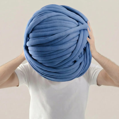 Person holding a large ball of cornflower color  tube yarn against a plain background