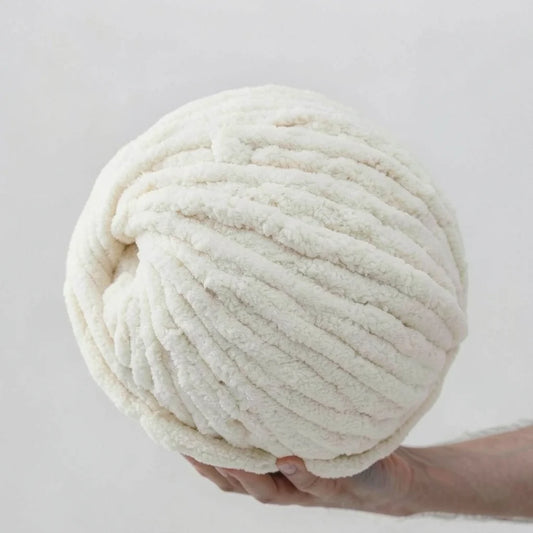 Large ball of cream chenille yarn held against a light gray background