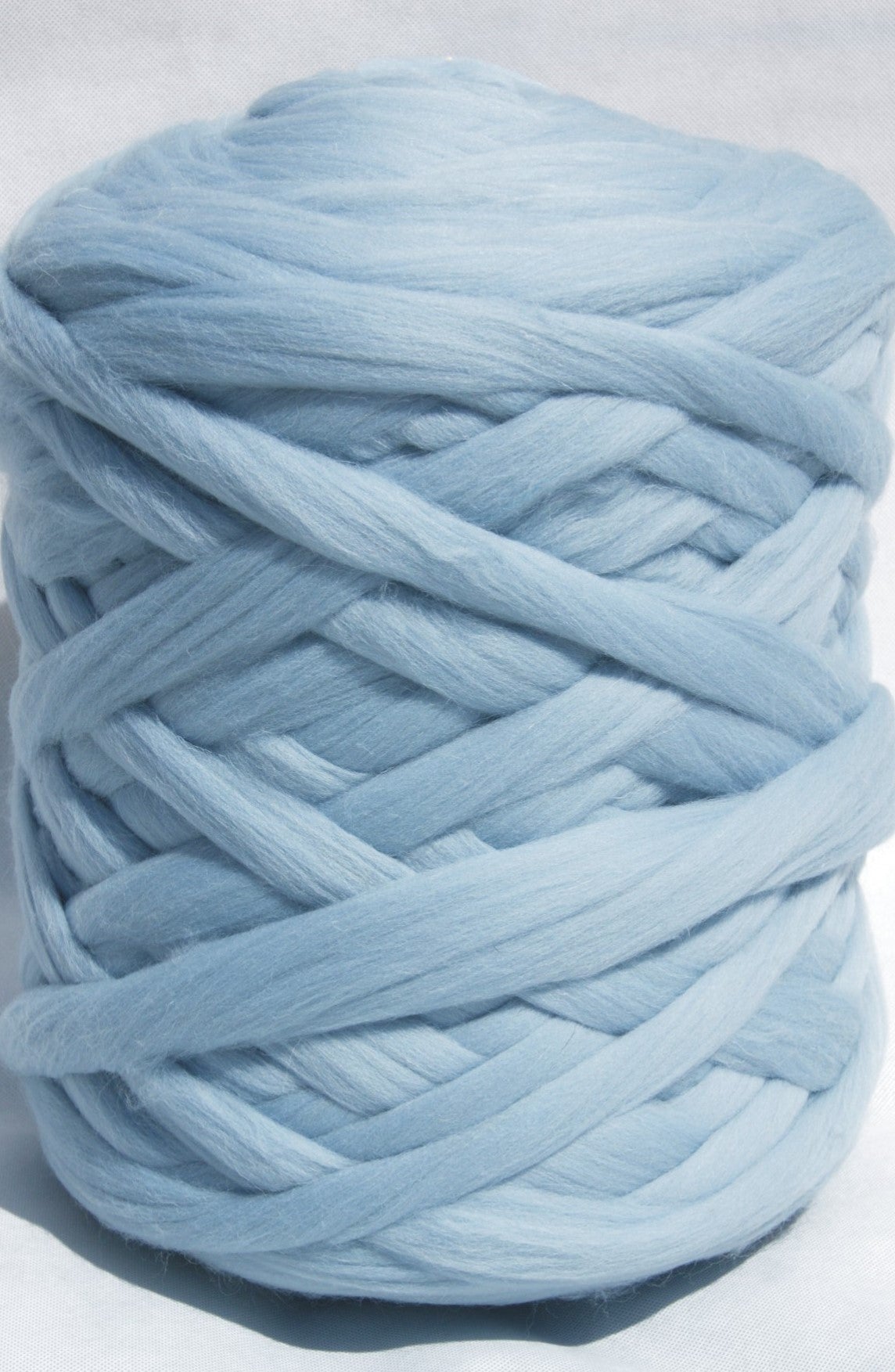 Light blue chunky wool yarn ball on a light gray background