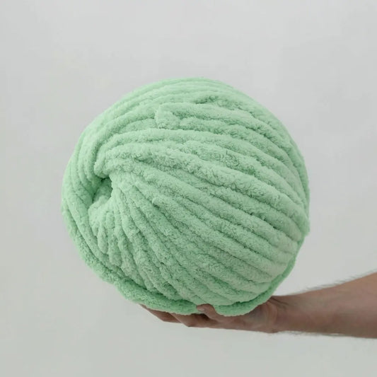 Large ball of mint chenille yarn held against a plain background