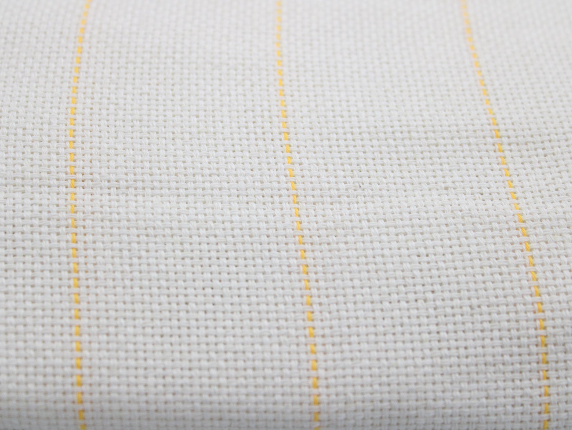 Close-up of a white monks cloth with three thin vertical yellow guidlines