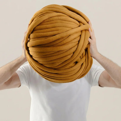 Man holding giant mustard color cotton tube yarn against beige background