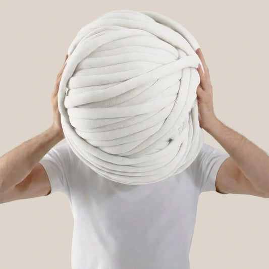 Person holding a giant ball of white  tube yarn against a beige background