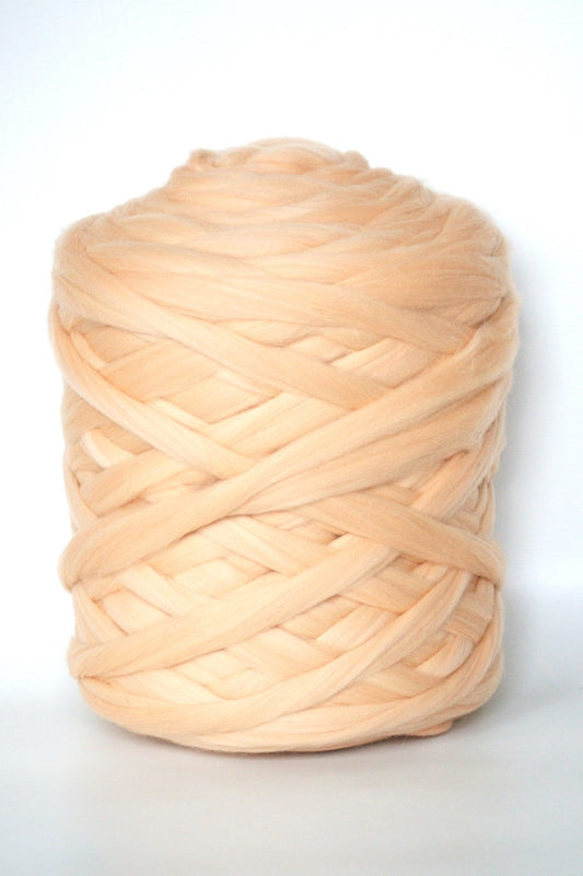 Large ball of peach-colored chunky yarn on a white background